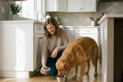 femme nourrissant son chien stérilisé avec une portion équilibrée dans une cuisine moderne
