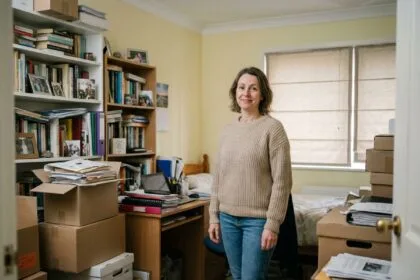 Femme dans un intérieur encombré avec des cartons de rangement empilés et des étagères débordantes de affaires personnelles