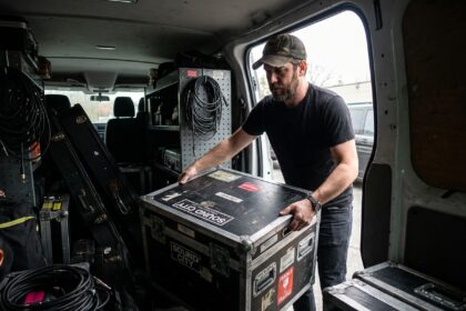 Musicien plaçant un flight case d'occasion usagé dans un fourgon de tournée, matériel de protection pour instruments en déplacement